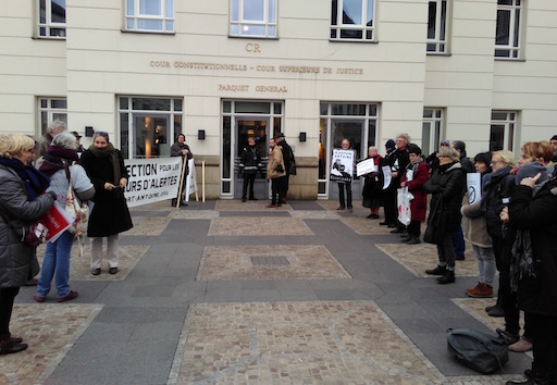 People holding signs and banners welcome Antoine in front of the court's entrance