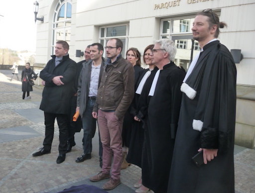 Photo de groupe des trois inculpés et de leurs avocats, sur le parvis de la cité judiciaire
