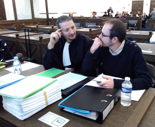 Antoine and his lawyer Mr Penning chatting in the courtroom, big files on the table before them